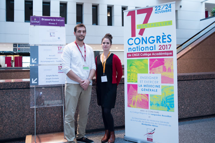 Un médecin et un interne devant une affiche du congrès CNGE